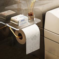 a white toilet sitting next to a bath tub filled with water and reeds on top of a glass shelf