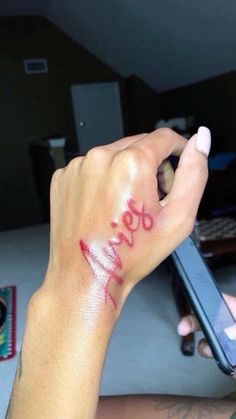 a person with red ink on their arm holding a cell phone