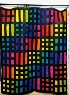 a multicolored quilt hanging on a wall