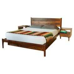 a bed sitting next to a night stand on top of a wooden table with two nightstands