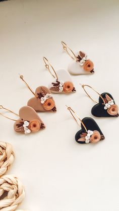 six pairs of earrings with flowers on them sitting on a white table next to rope