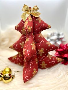 a red and gold christmas tree ornament next to other holiday decorations on white fur