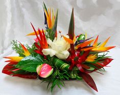 a bunch of flowers that are sitting on a white table cloth with leaves and flowers in the center