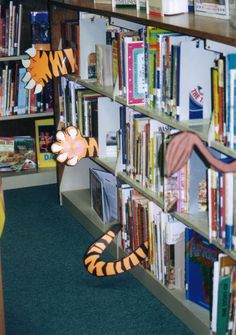 there is a stuffed tiger in front of the bookshelf with many books on it