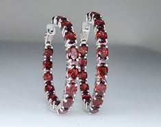 A pair of red garnet gemstone sterling silver hoop earrings.  Watch a video of this item Hoop Size: 37mm Metal: Sterling Silver Gemstone:  Garnet Closure: hinge post Fine Jewelry Hinged Gift, Red Sterling Silver Round Hoop Earrings, Red Sterling Silver Hoop Earrings, Formal Silver Gemstone Hoop Earrings, Classic Gemstone Hoop Jewelry, Classic Hoop Gemstone Jewelry, Red Hoop Jewelry For Formal Occasions, Silver Gemstone Hoop Earrings Fine Jewelry, Silver Hoop Earrings With Gemstones In Fine Jewelry Style