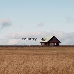 an old house in the middle of a field with a country word on it's side