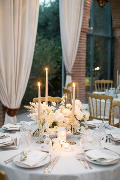 the table is set with white flowers and candles for an elegant dinner party or reception