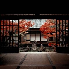 an open door with trees and rocks in the foreground, on which there is a red maple tree