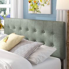 a bed with white sheets and blue walls in a room that has flowers on the wall