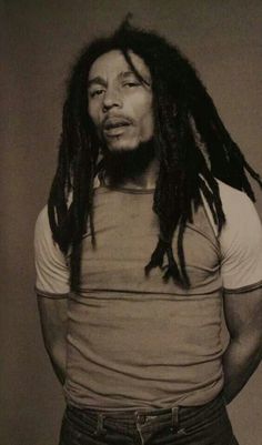 a man with dreadlocks standing in front of a wall