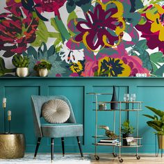 a living room with blue walls and colorful flowers on the wall behind a gray chair