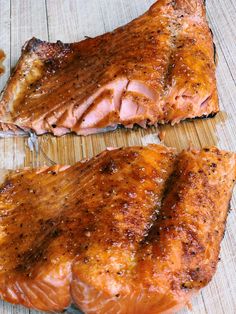 two pieces of salmon sitting on top of a wooden table