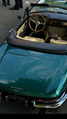 the interior of a green sports car is seen in this image, with people standing around it