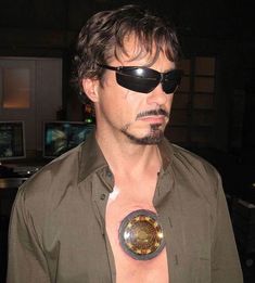 a man wearing sunglasses and holding a round object in his hand with an eye patch on it's chest