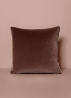 a brown velvet pillow on a pink background