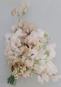 a bunch of flowers that are sitting on a table in front of a white wall