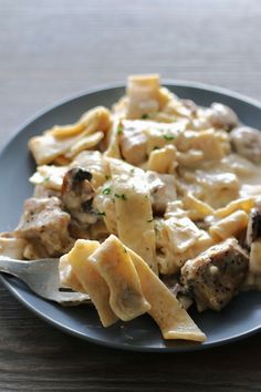 a plate with pasta and meat on it sitting on a table next to a fork