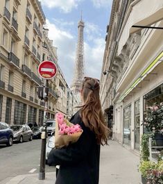 a woman is walking down the street with some doughnuts in her hand and looking at the eiffel tower