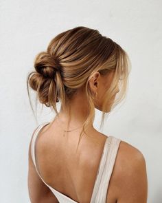 a woman with her back to the camera wearing a white tank top and gold earrings