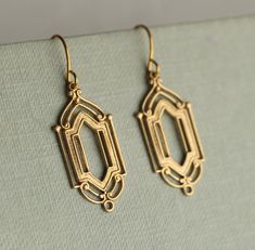 These great earrings are made from solid golden brass and feature a graduated art deco design.  They have the most wonderful, intricate detailing.   The earrings measure 30mm (just over an inch) in length and have  gold plated brass earwires.   This piece of jewellery comes packaged in a nice recycled gift box with a handmade tag, all ready to give or keep. 🖤 FASTER SHIPPING 🖤 Need this fast? We offer a Faster Shipping option here: https://www.etsy.com/uk/listing/100107311/faster-shipping-priority-post-upgrade 🖤 GIFT MESSAGE & WRAP SERVICE! 🖤 For those of you who are sending gifts straight to your loved one, we are happy to offer beautifully designed gift wrapping and to include a personal message from you in the package, printed on a sweet little hand-drawn notecard! https://www.etsy. 1920s Earrings, Gold Art Deco Earrings, Silk Purse, Geometric Chandelier, Gold Art Deco, Photo Locket, Handmade Tags, Art Deco Earrings, Gold Art