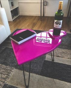 a pink table with a bottle of wine and glasses on it in a living room