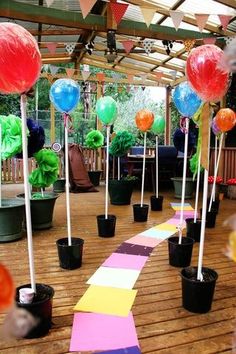 there are many balloons in the air on this wooden floored area with potted plants