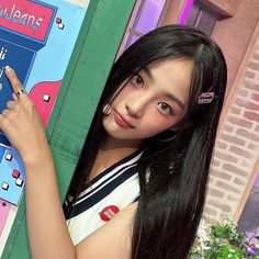 a girl is standing in front of a vending machine and pointing at the sign