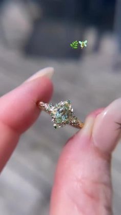 a person holding a ring in their left hand with a tiny diamond on it's finger