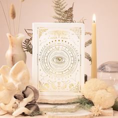 a table topped with flowers and candles next to a card that has an all seeing eye on it