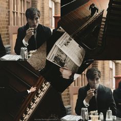 a man in a suit reading a newspaper while another man looks at his cell phone