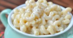 macaroni and cheese in a blue bowl on a wooden table with sprinkles