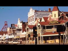 an old fashioned street scene with cars parked on the side and buildings in the background