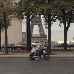 two people on a motorcycle passing by the eiffel tower in paris, france