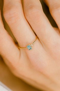 a woman's hand wearing a gold ring with an aqua topazte stone