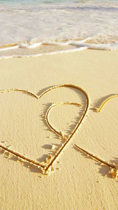 two hearts drawn in the sand at the beach