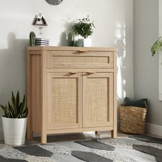 a wooden cabinet with plants on top and a clock mounted to the wall above it