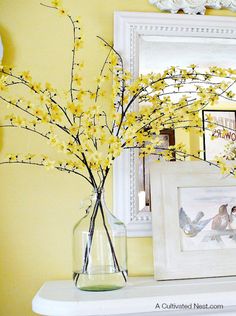 a vase with yellow flowers sitting on top of a white shelf next to a mirror