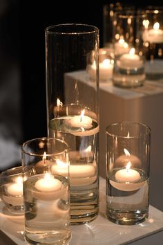 candles are lit in glass vases on a table