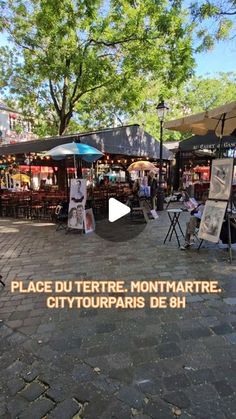 an outdoor market with tables and umbrellas on the sidewalk in front of it, surrounded by trees