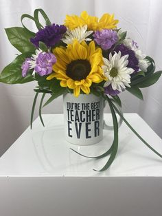 a bouquet of flowers sitting on top of a white table next to a sign that says you're the best teacher ever