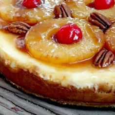 a pineapple upside down cake with pecans and cherries on top, sitting on a wooden table