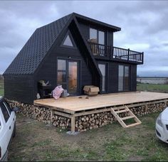 a small black house with a deck and car parked next to it