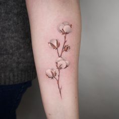 a woman's arm with cotton flowers tattooed on the back of her left arm