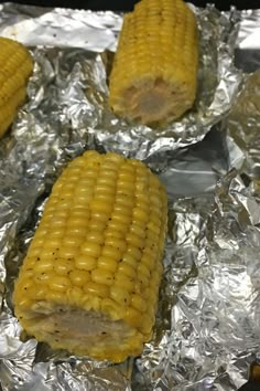 corn on the cob is sitting on tin foil and ready to be grilled