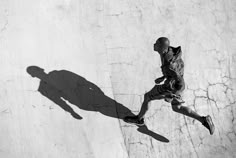 a man riding a skateboard up the side of a cement wall with his shadow on it