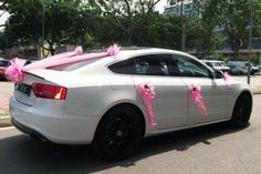 a white car is decorated with pink bows