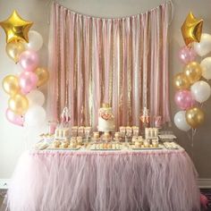 a pink and gold birthday party with balloons, cake and cupcakes on the table