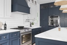 a kitchen with blue cabinets and white counter tops, an oven in the center island