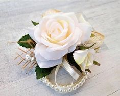 a white rose and pearls corsage on a table