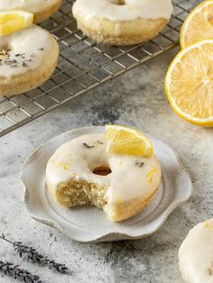 a lemon donut with a bite taken out of it on a plate next to some lavender sprigs